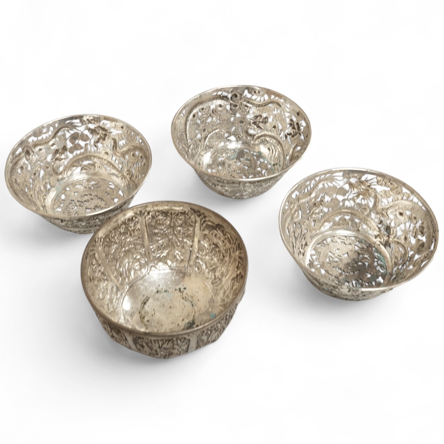 A set of three late 19th/early 20th century Chinese Export pierced white metal bowls, decorated with dragons, by Wang Hing, Hong Kong (lacking glass inserts?), diameter 12.5cm, together with one other similar Chinese Exp
